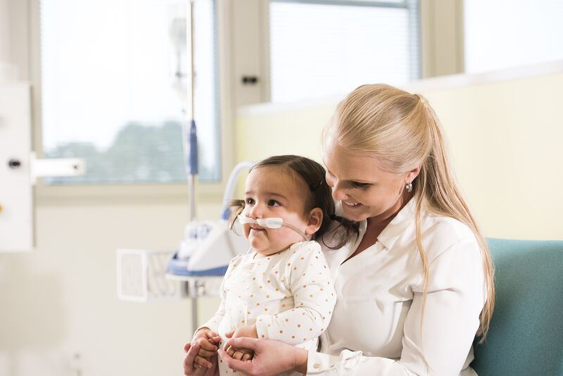 Mom holding kid having respiratory support via Fisher Paykel Optiflow Junior 2 Nasal cannula